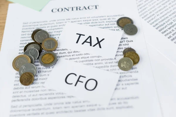 Papers with tax and cfo lettering on contract with coins — Stock Photo