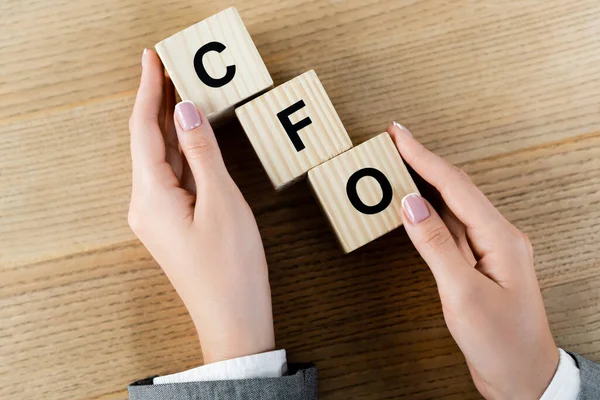 Вид зверху бізнес-леді, що тримає дерев'яні кубики з літерами cfo — стокове фото