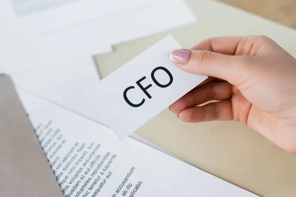 Vista recortada de la mujer sosteniendo papel con letras cfo - foto de stock