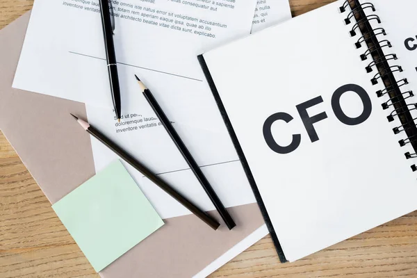 Вид зверху ноутбука з клаптиком cfo біля олівців і документів — стокове фото