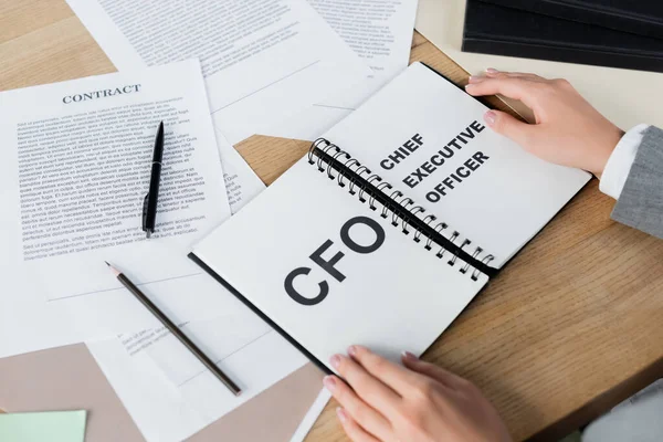 Cropped view of woman holding notebook with cfo and chief executive officer lettering — Stock Photo