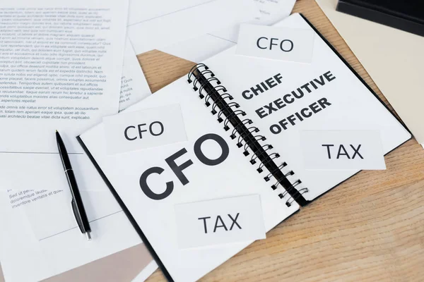 Draufsicht auf Notizbuch mit Schriftzug cfo und Vorstandsvorsitzender in der Nähe von Dokumenten auf dem Schreibtisch — Stockfoto