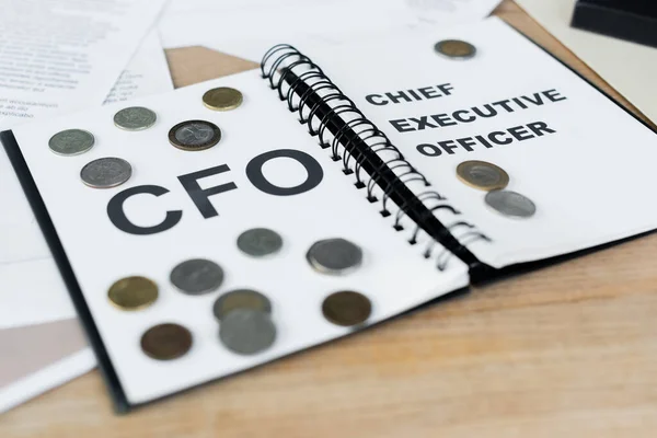 Monedas de plata y oro en cuaderno con letras de cfo y director ejecutivo - foto de stock