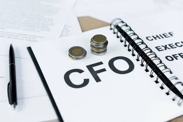 Silver and golden coins on notebook with cfo lettering near pen — Stock Photo