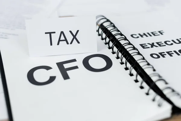 Close up of paper with tax lettering near notebook with cfo word — Stock Photo