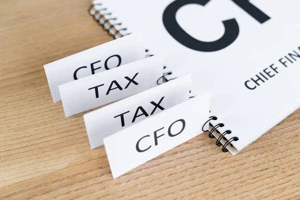 Papiers avec taxe et lettrage cfo près ordinateur portable sur le bureau — Photo de stock