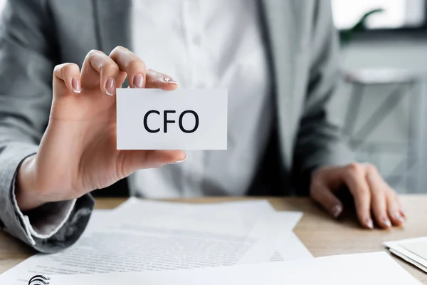 Cropped view of woman holding paper with cfo lettering in office — Stock Photo