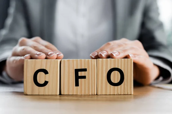 Vista ritagliata di donna che tiene cubi di legno con scritte in cfo in ufficio — Foto stock