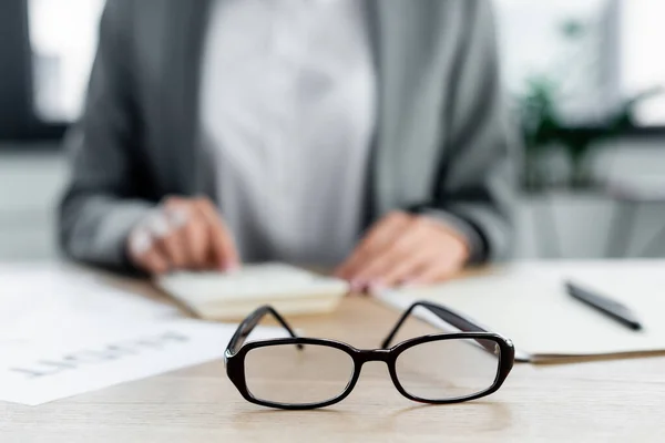 Selective focus of glasses near chief financial officer in office — Stock Photo