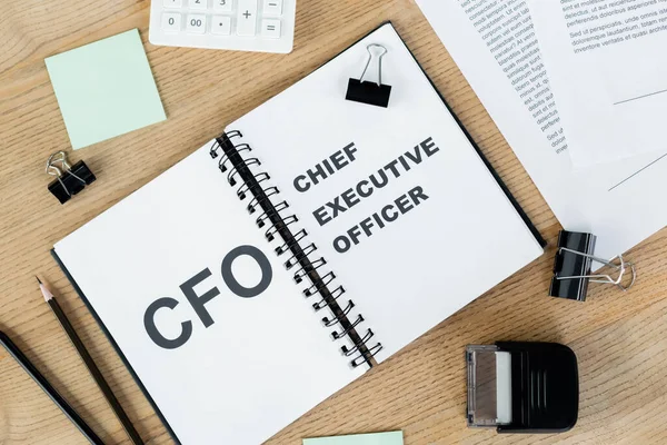 Top view of notebook with cfo and chief executive officer lettering near documents and stationery — Stock Photo