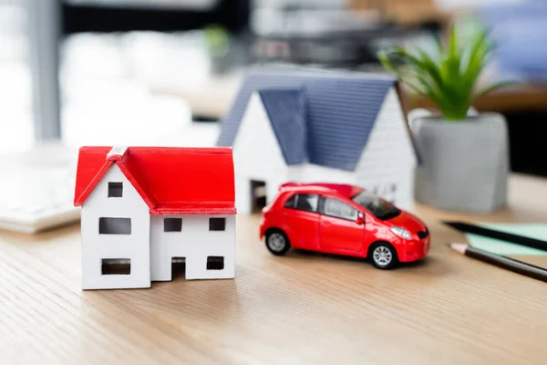 Modelos de casa cerca de coche de juguete en la mesa, concepto de inspección de impuestos - foto de stock