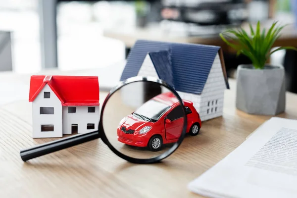 Modelos de casa cerca de lupa y coche de juguete en la mesa, concepto de inspección de impuestos — Stock Photo