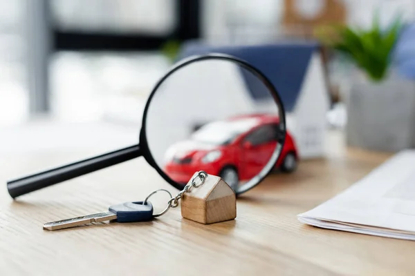 Llave y lupa cerca del coche borroso del juguete en la mesa, concepto de inspección fiscal - foto de stock