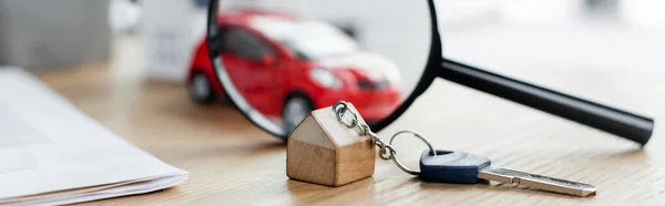 Llave y lupa cerca del coche borroso del juguete en la mesa, bandera — Stock Photo
