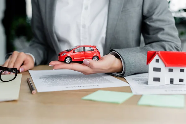 Vista cortada do inspetor fiscal segurando carro de brinquedo perto de documentos na mesa — Fotografia de Stock