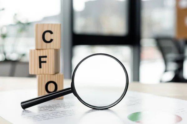 Magnifying glass near cubes with cfo letters and document on desk — Stock Photo