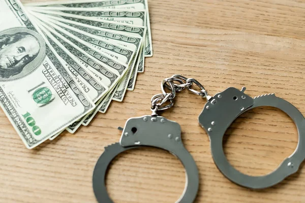 Top view of handcuffs and dollar banknotes on desk — Stock Photo
