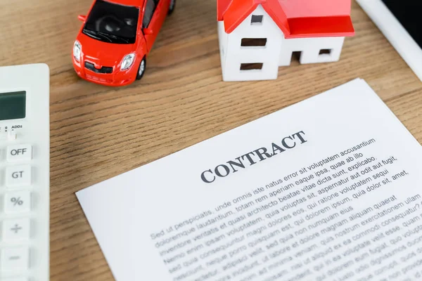 Top view of contract near house model and toy car on table — Stock Photo