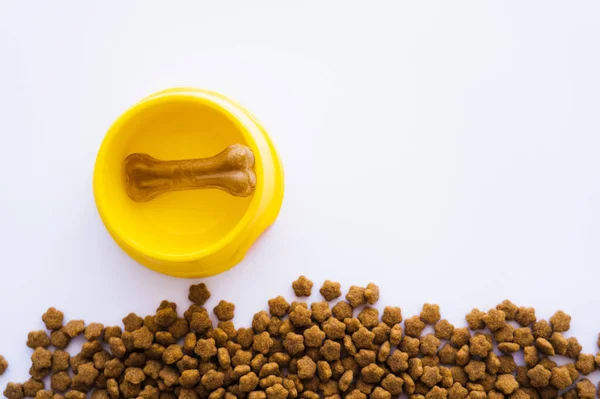 Vista dall'alto del trattamento a forma di osso cane in una ciotola di plastica vicino cibo per animali domestici — Foto stock