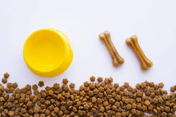 Vista superior de ossos em forma de cão trata perto de tigela de plástico e alimentos para animais de estimação — Fotografia de Stock