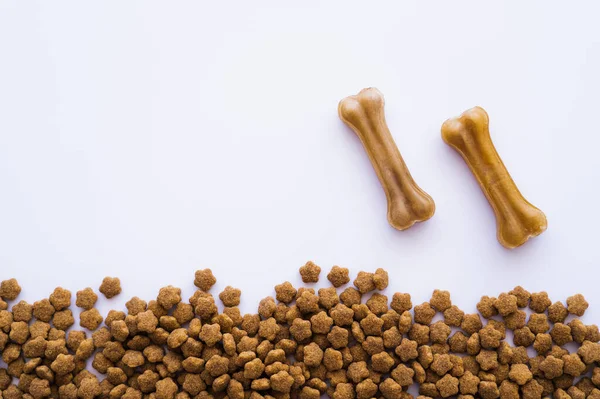 Top view of bone shaped pet treats near pet food on white — Stock Photo