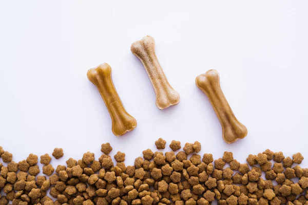 Top view of bone shaped dog treats near pet food — Stock Photo