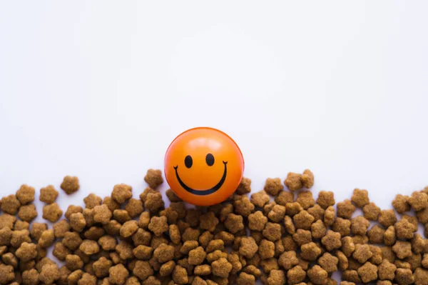 Bola con emoticono sonriente cerca de alimentos para mascotas aislados en blanco - foto de stock