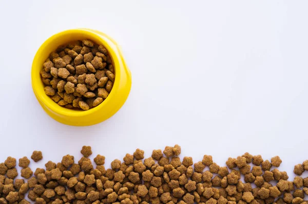 Vue du dessus du bol en plastique jaune avec nourriture sèche pour animaux isolés sur blanc — Photo de stock