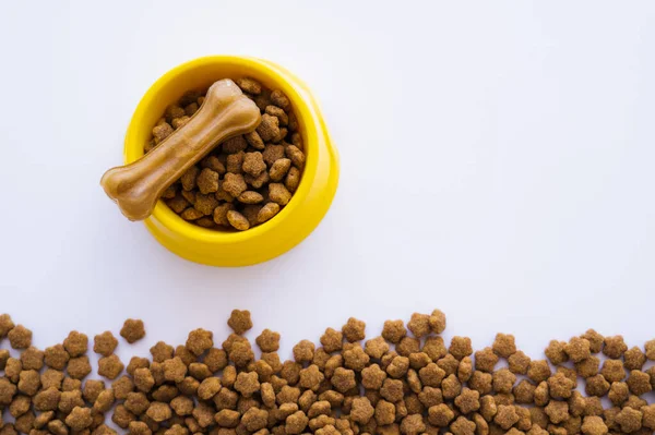 Vista dall'alto di ciotola di plastica gialla con cibo per animali domestici e trattamento del cane isolato su bianco — Foto stock