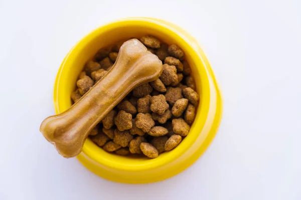 Vista superior del tazón amarillo con comida para mascotas y tratamiento para perros aislado en blanco - foto de stock