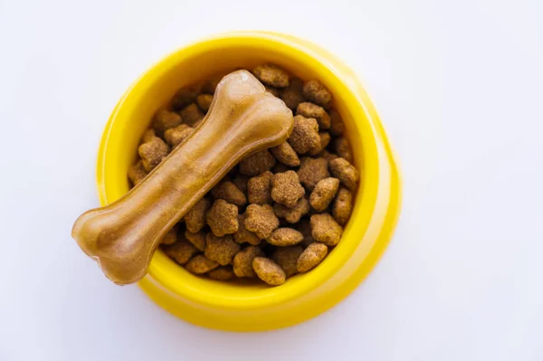 Vue du dessus du bol jaune avec nourriture pour animaux de compagnie et gâterie pour chien isolé sur blanc — Photo de stock