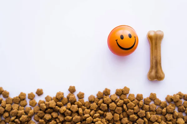 Vista superior de la bola con emoticono sonriente cerca de alimentos para mascotas y tratar en forma de hueso aislado en blanco - foto de stock