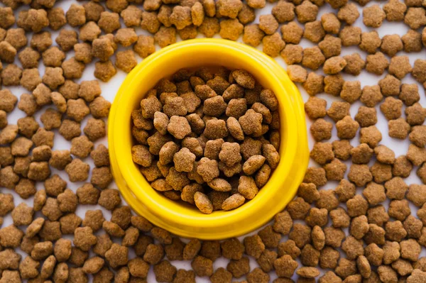 Vista superior de comida seca para mascotas en un tazón amarillo de plástico - foto de stock