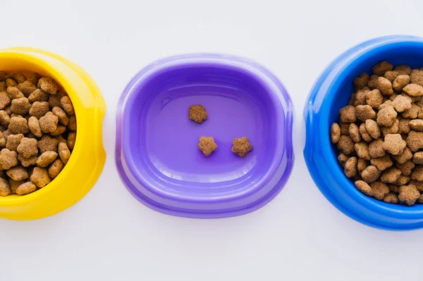 Top view of colorful bowls with different pet food isolated on white — Stock Photo