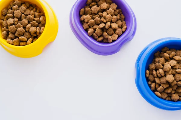 Top view of colorful bowls with different pet food isolated on white — Stock Photo