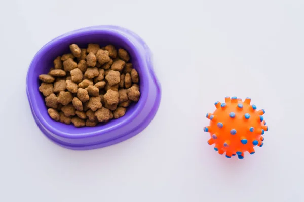 Vista superior de brinquedo de borracha perto da tigela com alimentos para animais de estimação em branco — Fotografia de Stock