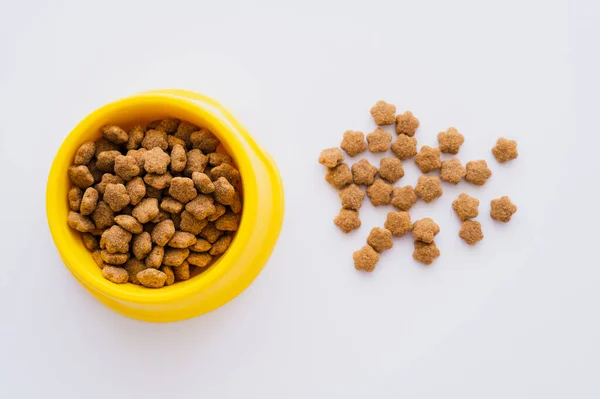 Vue de dessus des aliments secs et croquants pour animaux de compagnie près du bol isolé sur blanc — Photo de stock