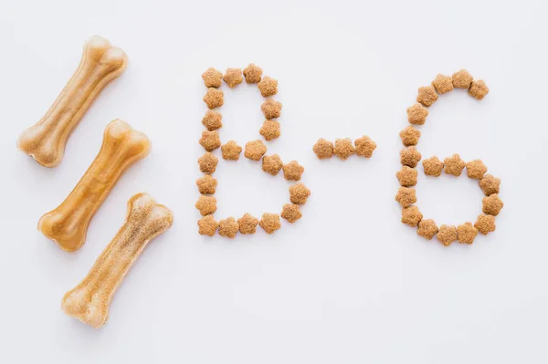 Leigos planos de palavra feita de alimentos secos para animais de estimação perto de ossos em forma de animais de estimação isolados em branco — Fotografia de Stock