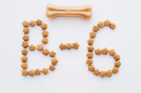 Flat lay of word made of dry pet food near bone shaped pet treat isolated on white — Stock Photo