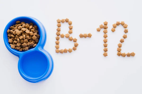 Vista superior de la palabra hecha de comida seca para mascotas cerca de cuencos en blanco - foto de stock