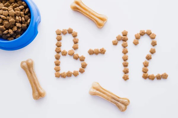 Vista superior da palavra feita de alimentos secos para animais de estimação perto da tigela e guloseimas em forma de osso no branco — Fotografia de Stock