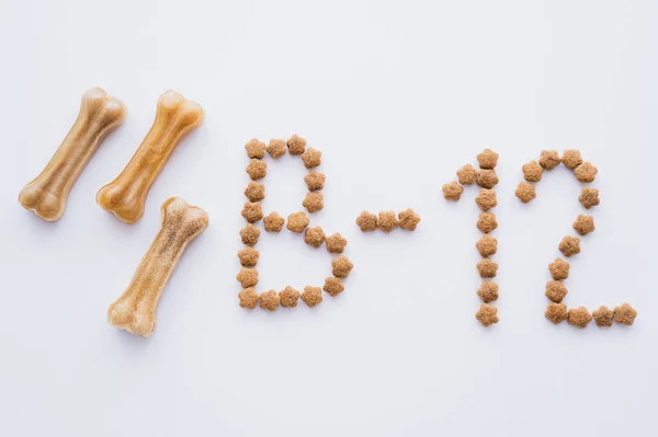 Top view of word made of dry pet food near bone shaped treats on white — Stock Photo