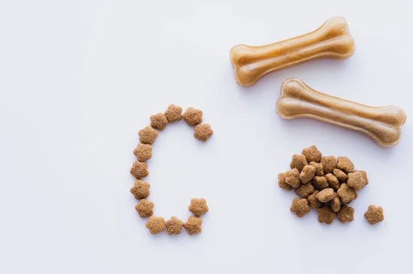 Vista superior de ossos em forma de animais de estimação trata perto de alimentos secos para animais de estimação e carta isolada em branco — Fotografia de Stock