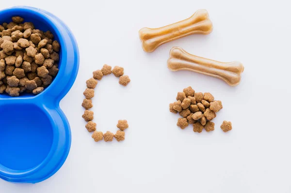 Vista superior de ossos em forma de animais de estimação trata perto de alimentos para animais de estimação e carta isolada em branco — Fotografia de Stock