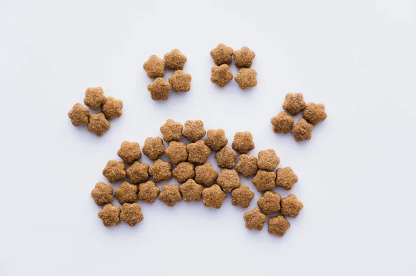Vista superior da forma da pata feita de alimentos secos para animais de estimação isolados em branco — Fotografia de Stock
