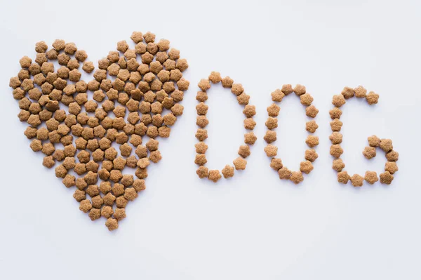 Vista superior de alimentos secos para animais de estimação em forma de coração perto de lettering cão isolado em branco — Fotografia de Stock