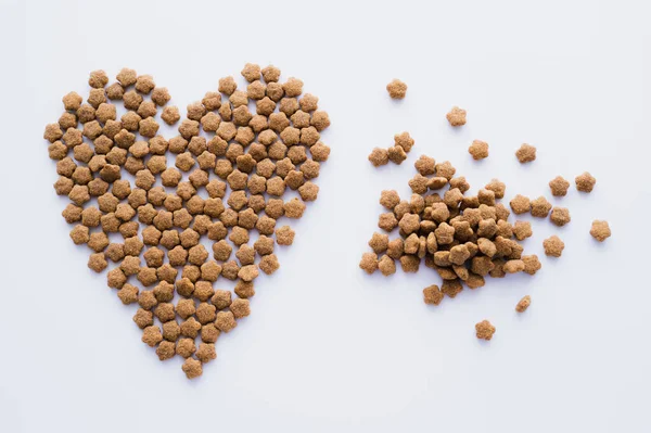 Vista dall'alto del cibo secco per animali domestici a forma di cuore isolato su bianco — Foto stock