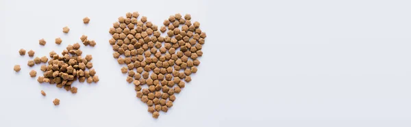 Vista superior de alimentos secos para animais de estimação em forma de coração isolado em branco, banner — Fotografia de Stock