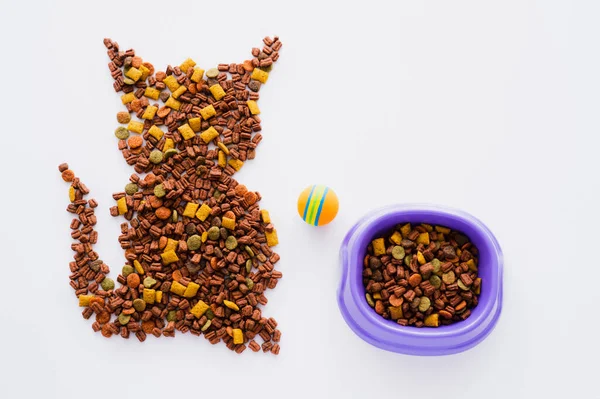 Vista dall'alto della forma del gatto fatto da cibo per animali domestici asciutto vicino ciotola e palla isolata su bianco — Foto stock