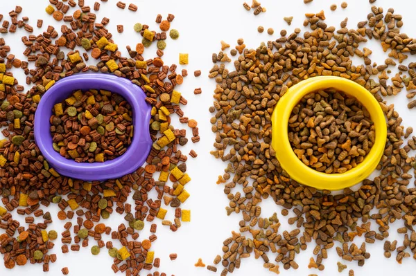 Top view of pet food in yellow and purple bowls isolated on white — Stock Photo